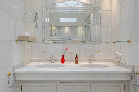 Elegantes Badezimmer mit Doppelwaschbecken, einem dekorativen Spiegel und luxuriösen Akzenten.