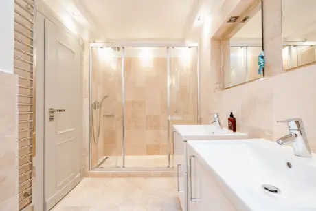 Modernes Badezimmer mit Dusche, Doppelwaschbecken und großem Spiegel.