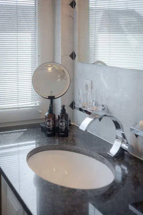 Luxuriöses Badezimmer im Hotel mit Waschbecken, Spiegel und eleganten Pflegeprodukten.