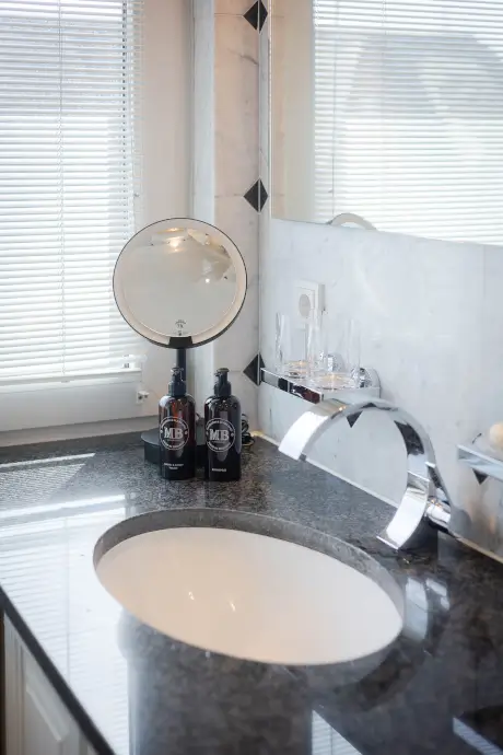 Elegantes Badezimmer mit Spiegel und hochwertigen Pflegeprodukten.
