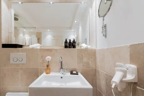 Modernes Badezimmer mit Waschbecken, Spiegel und Pflegeprodukten.