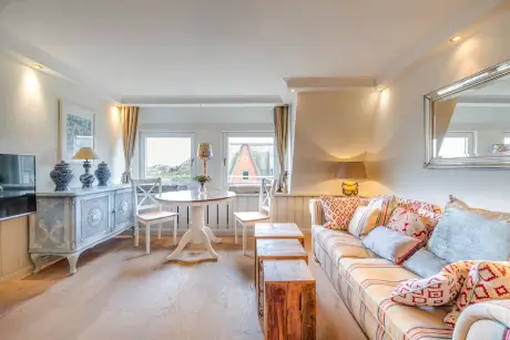 Gemütlicher Hotelzimmer mit Sofa, Esstisch und Fenster in Kampen, Sylt.