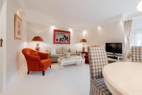 Stilvolle Hotel-Lounge mit einem gemütlichen Sofa, Sesseln, Kunstwerk und modernem Fernseher.