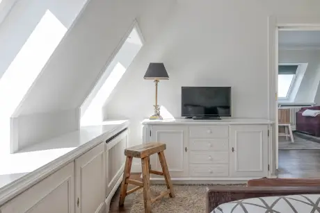 Elegantes Hotelzimmer mit einer Lampe, Fernseher und Holzstuhl im Hotel Stadt Hamburg.