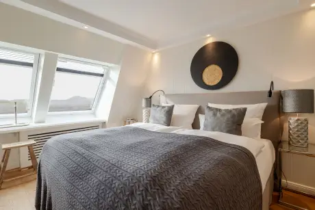 Gemütliches Hotelzimmer mit einem Doppelbett, stilvollen Lampen und eleganter Dekoration.