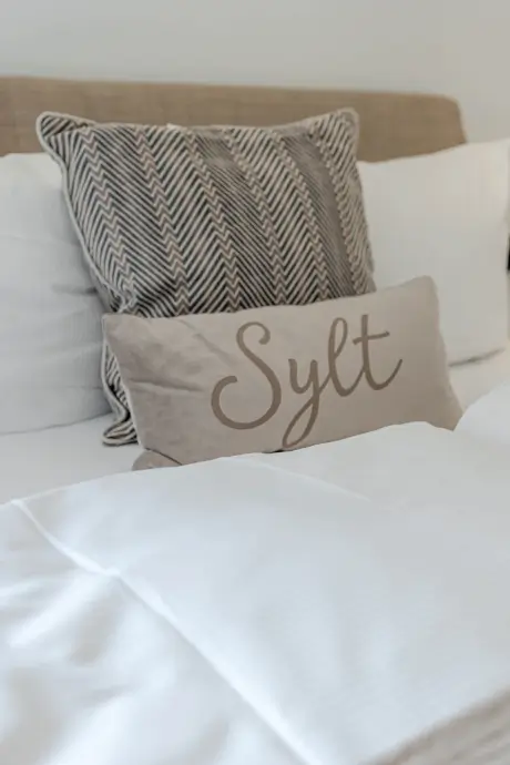 Gemütliches Hotelzimmer im Stadt Hamburg in Sylt mit dekorativen Kissen.