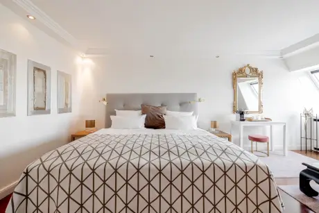 Luxuriöses Hotelzimmer mit stilvollem Bett, dekorativem Spiegel und eleganten Möbeln im Hotel Stadt Hamburg.