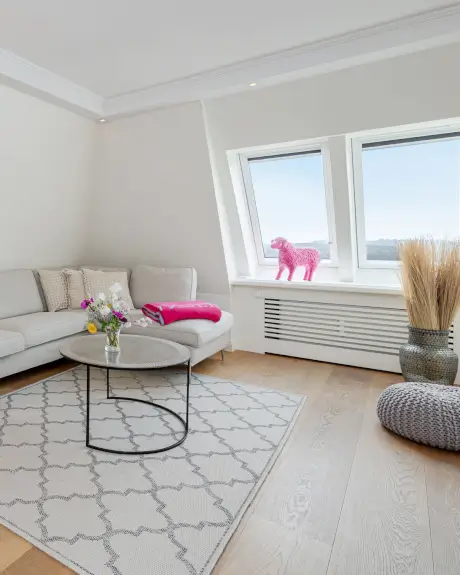 Gemütliches Hotelzimmer im Hotel Stadt Hamburg mit einer grauen Couch, pinkem Dekorationspferd und stilvollem dekor.