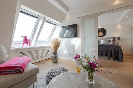 Stylisches Hotelzimmer mit einer rosa Schafdekoration, gemütlichem Bett und modernen Annehmlichkeiten.