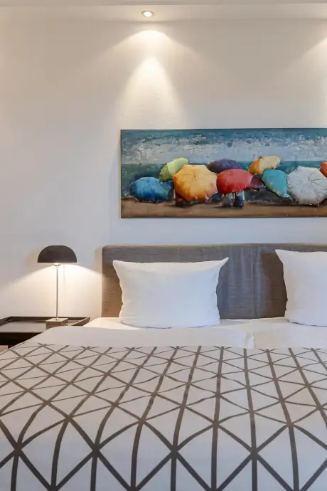 Gemütliches Hotelzimmer mit farbenfrohem Regenschirmgemälde und stilvollem Dekor.