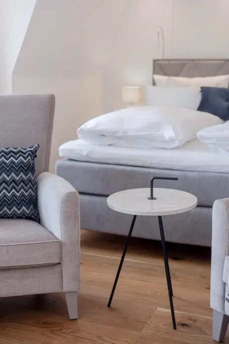 Gemütliches Hotelzimmer mit moderner Einrichtung, einschließlich eines stilvollen Stuhls und einem bequemen Bett.