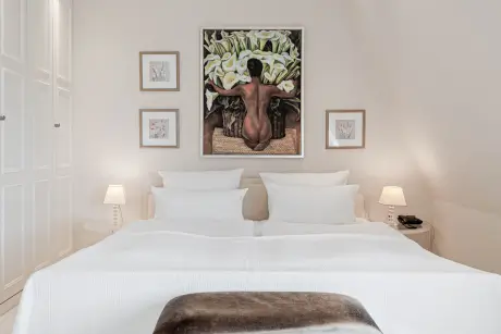 Stilvolles Hotelzimmer mit Doppelbett und schöner Kunst an der Wand.