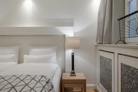 Gemütliches Hotelzimmer mit Bett, Nachttisch und stilvoller Lampe.