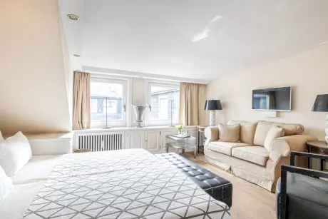 Ein gemütliches Hotelzimmer mit einem Bett, Sofa und natürlichem Licht von großen Fenstern.