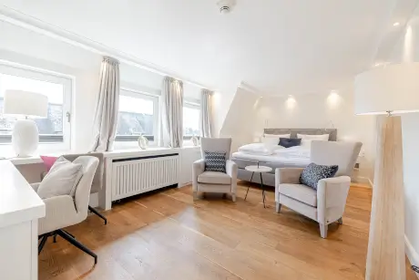 Elegantes Hotelzimmer im Hotel Stadt Hamburg mit Bett, Stühlen und Fenster.
