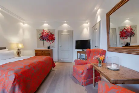 Elegantes Hotelzimmer im Hotel Stadt Hamburg mit rotem Bettbezug und Kunstwerken.