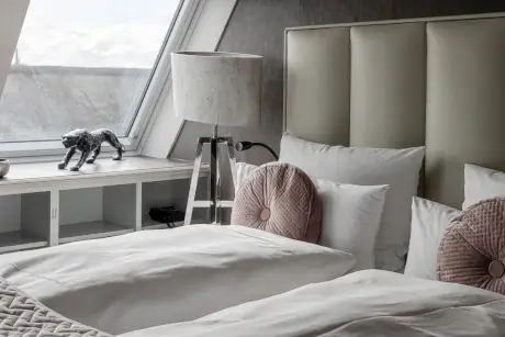 Gemütliches Hotelzimmer mit stilvollen Bettwäsche und Lampe im Hotel Stadt Hamburg, Kampen, Sylt.