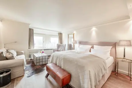 Elegantes Hotelzimmer mit komfortablem Bett, stilvollem Sofa und Glas-Kaffeetisch.