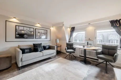 Modernes Hotelzimmer in Kampen mit stilvollem Sofa, Stühlen und Deko.