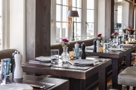 Tisch mit gedecktem Geschirr und Blumen im Restaurant des 12.18. Hotel Stadt Hamburg.