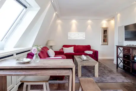 Modernes Wohnzimmer im Hotel Stadt Hamburg mit rotem Sofa, Holztisch und gemütlichem Dekor.